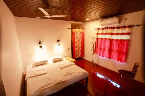 a bedroom with a bed and a red curtain at Marari John Villa in Mararikulam