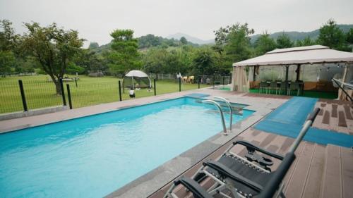 a swimming pool with chairs and a gazebo at Wonju Gwirae 630 Dog Pool Villa in Yongdang