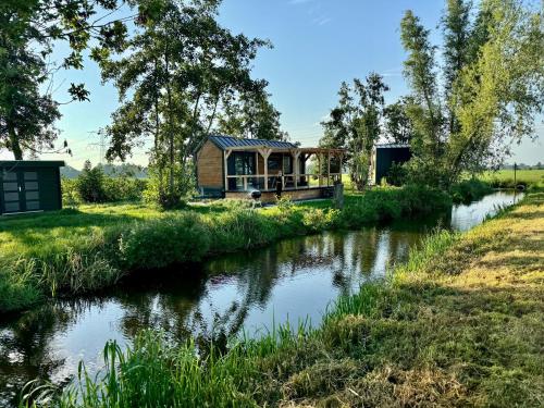 a holiday house on a river with a view of it at TinyHouse Ochtendgloren in Haastrecht