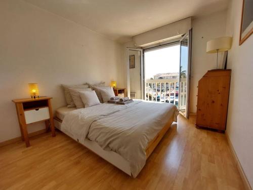 une chambre avec un grand lit et une grande fenêtre dans l'établissement L Escapade T2 Port Fréjus, à Fréjus