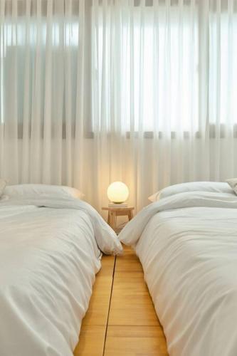 a bedroom with two beds and a lamp on the floor at Haru Stay in Seoul