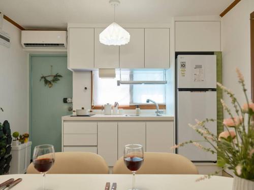 a kitchen with a table with two glasses of wine at Haru Stay in Seoul