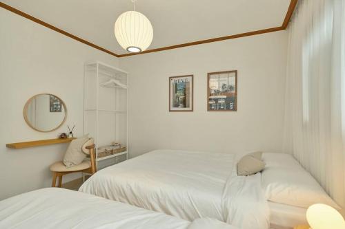 a white bedroom with two beds and a mirror at Haru Stay in Seoul