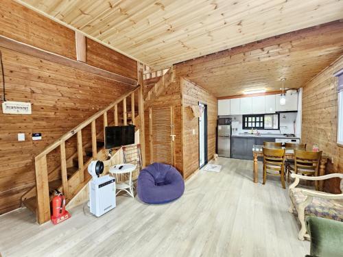 a living room with wooden walls and a dining room at Tree Story Pension in Seogwipo