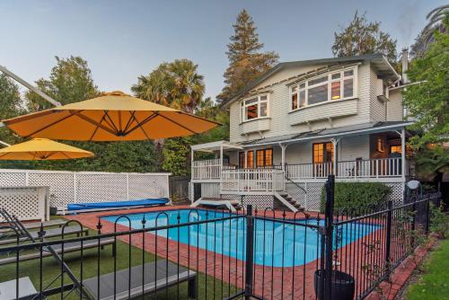 a house with a pool and an umbrella at Camellia House - Elevator Access, Swimming, and Spa Pools in Nelson