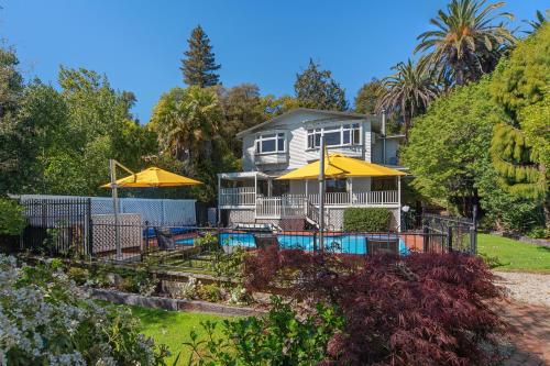 a house with a pool and umbrellas at Camellia House - Elevator Access, Swimming, and Spa Pools in Nelson