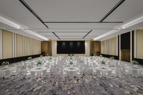 a banquet hall with white tables and chairs and a screen at Crowne Plaza Kunshan East by IHG in Kunshan
