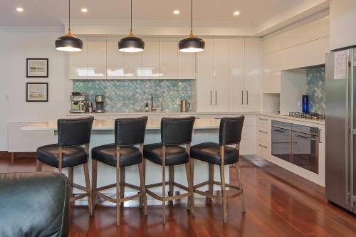 a kitchen with black chairs and a kitchen island at Camellia House - Elevator Access, Swimming, and Spa Pools in Nelson