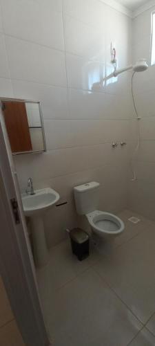 a white bathroom with a toilet and a sink at hostel casa 2 in Araraquara
