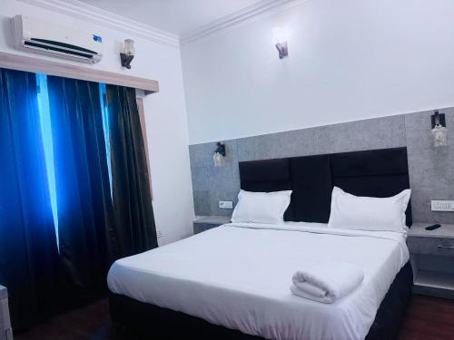 a bedroom with a large white bed with blue curtains at Staybook The Rudveda Resort - Free High Tea near Pool Area in Rāmnagar