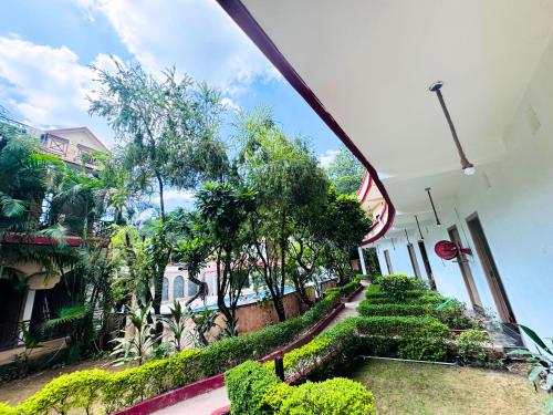 a view of a house with trees and a walkway at Staybook The Rudveda Resort - Free High Tea near Pool Area in Rāmnagar