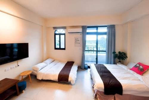 a hotel room with two beds and a flat screen tv at 雀居民宿 in Yuli