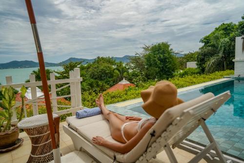 a woman in a hat laying in a chair next to a swimming pool at Soul Villas - Beachfront Private Pool Villas, Phuket Nature Retreat in Panwa Beach