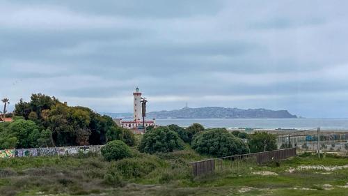 un phare au loin avec l'océan en arrière-plan dans l'établissement Departamento Jardines del Pacifico, à La Serena