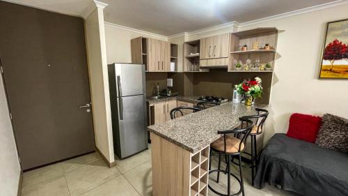 une petite cuisine avec un comptoir et un réfrigérateur dans l'établissement Departamento Jardines del Pacifico, à La Serena