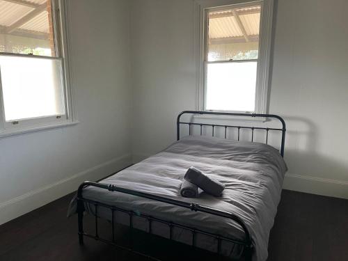 a bed in a white room with two windows at The Eagle's Nest in Manilla