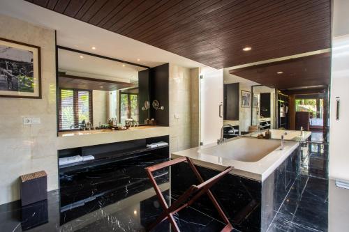 a bathroom with a large tub and a large mirror at Sanctoo Suites & Villas in Gianyar