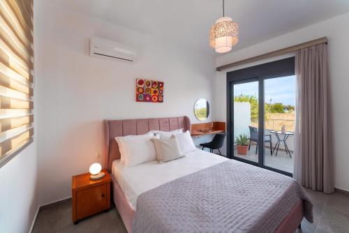 a bedroom with a bed and a balcony with a table at Lotus Luxury Apartments in Kremasti