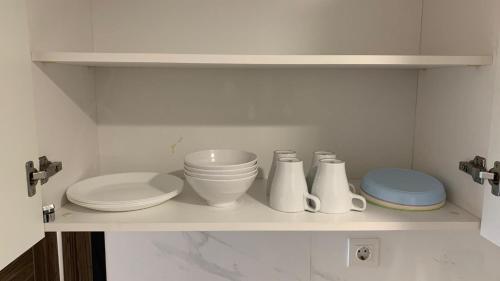 a kitchen shelf with plates and bowls on it at 2BR Apartment - Sky House BSD Next to Aeon Mall and ICE in Samporo