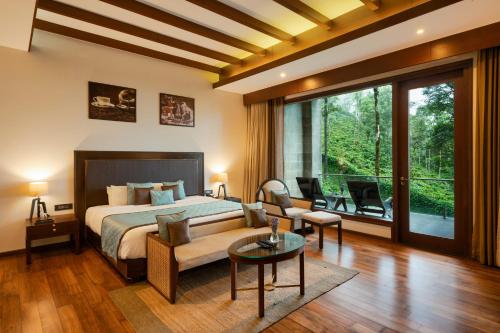 a bedroom with a bed and a large window at Trivik Hotels & Resorts, Chikmagalur in Chikmagalūr