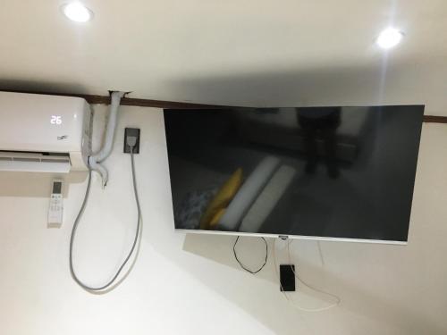 a tv hanging on a wall with a cord at Stay in Manila, Cambridge Village in Cainta