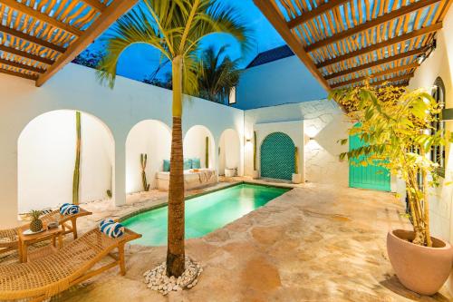 an indoor pool with a palm tree in a house at Villa Aurelia - 2 Bedrooms Rooftop Villa in Canggu in Canggu