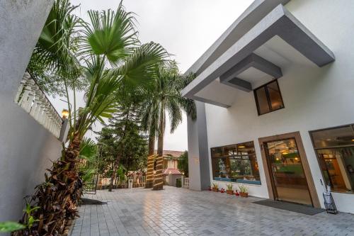 a house with a courtyard with palm trees in front of it at Sterling Panchgani in Panchgani