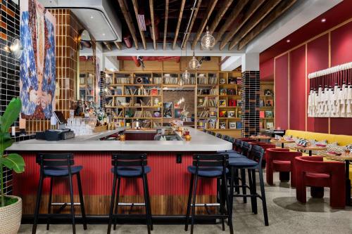 a bar in a restaurant with red walls and stools at Motto By Hilton Bentonville Downtown in Bentonville