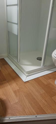 a glass shower door in a room with a wooden floor at Appartement Bagnères-de-Luchon T2 nuitée-semaines in Luchon