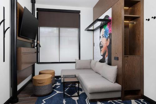a living room with a couch and a tv at Motto By Hilton Bentonville Downtown in Bentonville