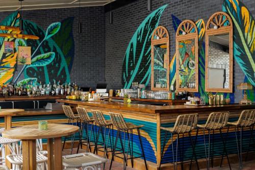 a bar with chairs and a wall with paintings at Motto By Hilton Bentonville Downtown in Bentonville
