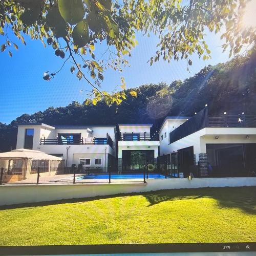 a large white house in front of a mountain at Wonju Gwirae 630 Dog Pool Villa in Yongdang