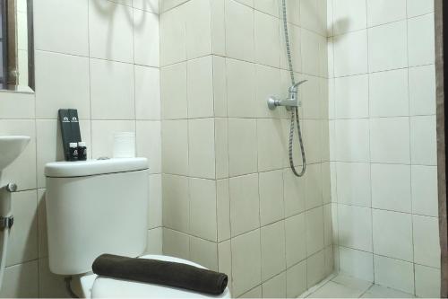 a white bathroom with a shower and a toilet at Convenient Studio Apartment at Vida View Makassar By Travelio in Pampang