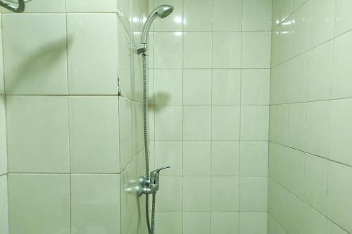 a shower with a glass door with a shower head at Convenient Studio Apartment at Vida View Makassar By Travelio in Pampang