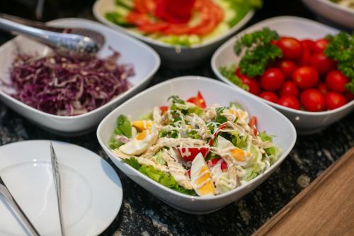 a table topped with bowls of salad and vegetables at Serene Central Hotel in Hanoi