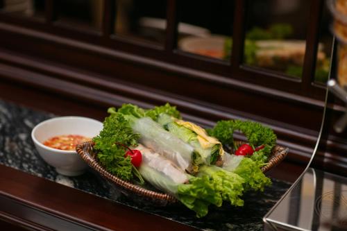 a bowl of lettuce and meat with a bowl of sauce at Serene Central Hotel in Hanoi