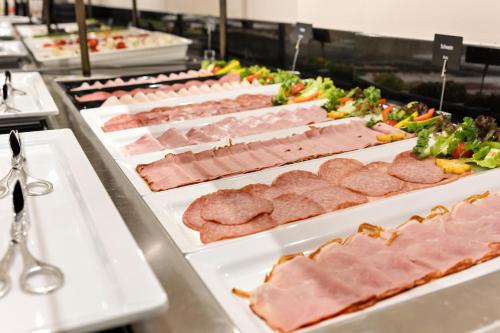 a buffet line of meats and vegetables on plates at Austria Trend Parkhotel Schönbrunn Wien in Vienna