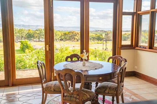 a dining room with a table and chairs and windows at Condor Estate Spacious with Vineyard & Fireplace in Maslin Beach