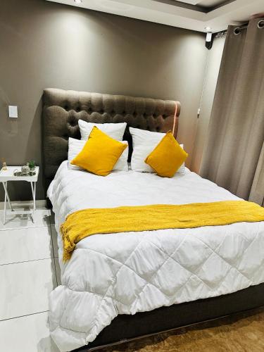 een slaapkamer met een groot bed met gele kussens bij West Home Rest in Westonaria