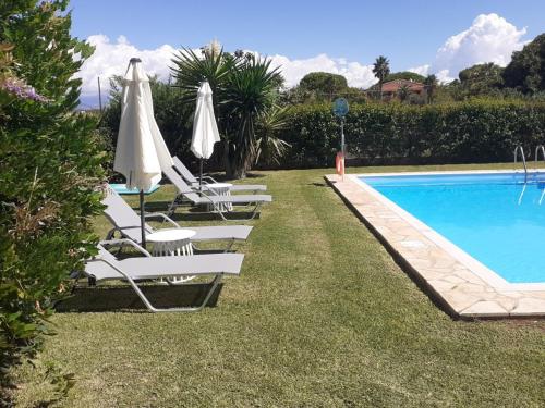 a row of lawn chairs with umbrellas next to a swimming pool at Villa Filia in Almiros Beach