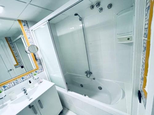 a white bathroom with a shower and a sink at Apartamento Aljaralto Sevilla in San Juan de Aznalfarache