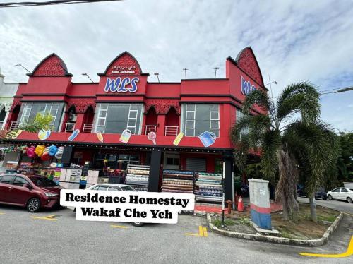 a red building with a sign in front of it at Residence Homestay Wakaf Che Yeh in Kota Bharu