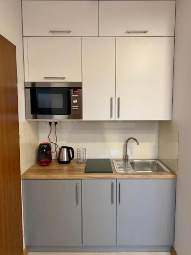 a kitchen with white cabinets and a microwave at Zielona Ostoja - Pokoje i Apartamenty in Nowa Sarzyna