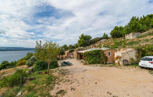 a house with a car parked next to a body of water at Awesome Home In Nerezisca With Wifi in Nerežišća
