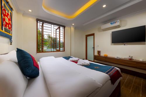a bedroom with a large white bed and a flat screen tv at Sapa TT Homestay in Sa Pa