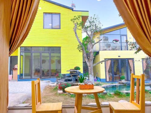 a yellow house with a table and chairs in front of it at Linh Anh Homestay MC - by BAY LUXURY in Mộc Châu