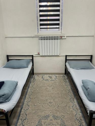 two beds in a room with a window and a rug at Hostel KG in Bishkek