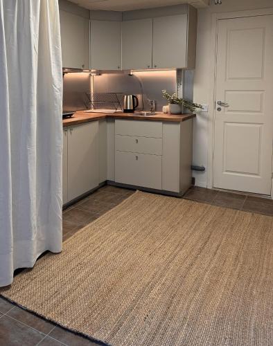 a kitchen with white cabinets and a door and a rug at Nomad City in Stockholm