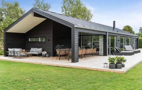 a black house with a wooden deck with furniture at Amazing Home In Væggerløse With Sauna in Marielyst