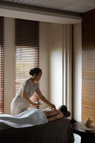 a woman getting a mans massage in a hotel room at Dusit Thani Manila in Manila